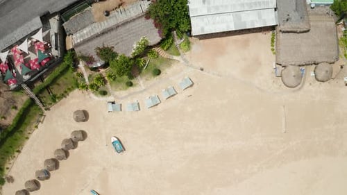 Birds-eye view descending drone shot over a bungalow hotel in Tofo, Mozambique.