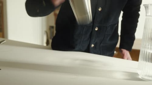 Man Shaking Cocktail Shaker in Bright Home Kitchen