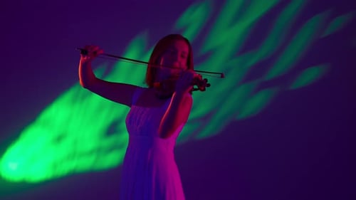 Woman in White Dress Plays Violin Under Green Light