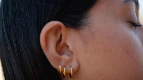Woman's Ear with Golden Hoop Earrings Close Up