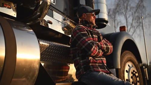 American Caucasian Trucker Seating on His Semi Truck Steps