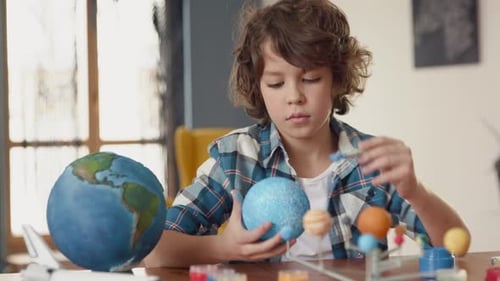 Young Boy Painting Model Solar System at Home