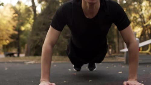 Closeup of a Young Athletic Caucasian Guy in Sportswear Doing Pushups on the Playground in the Park