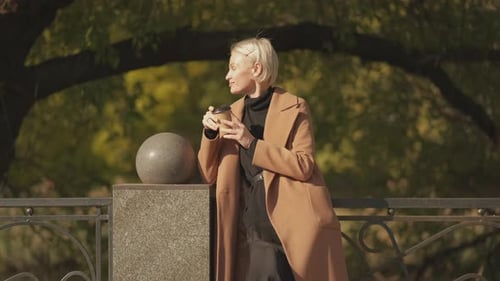 Stylish Woman Relaxing in Urban Park with Coffee