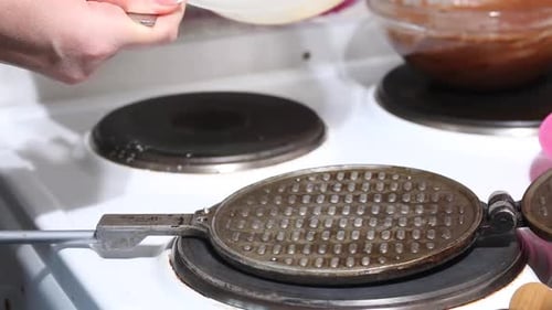 A Woman Puts Dough On A Hot Waffle Iron. Preparing Waffle Cones. Shot Close Up.