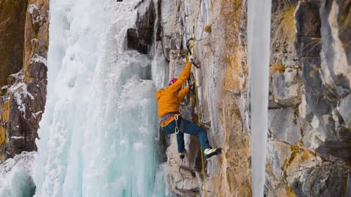 Man Ice Climbing Rocky Mountain Waterfall in Winter