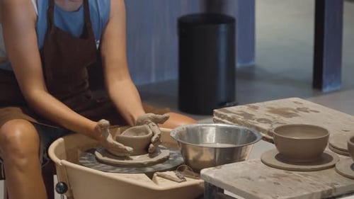 Woman Shaping Mound of Clay Bowl on Potter Wheel During Pottery Workshop - slow motion pan
