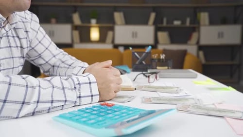 Man Counts Cash at Bright Desk in Home Office