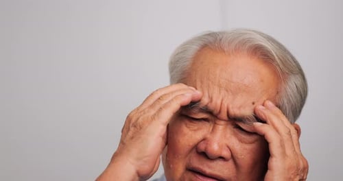 Asian old man with migraine headache. Elderly man suffering from a headache.