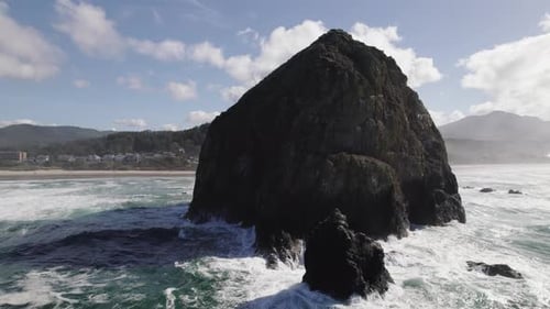 Foamy seawater crashes against Haystack Rock in Oregon