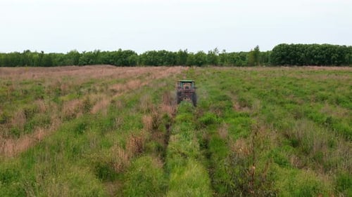 Drone Follows Tractor Spraying Fertilizer Across Agricultural Field
