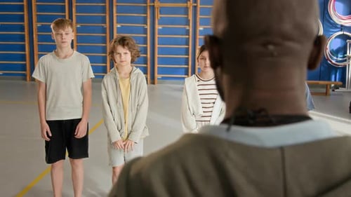 Children in Row in School Gym and Listening to Teachers Instruction