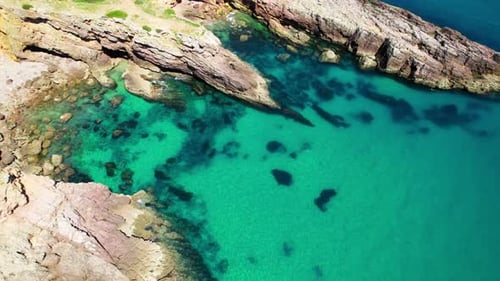 Cove With Rocky Cliffs, Calm And Crystal Clear Water On A Sunny Day. - aerial shot