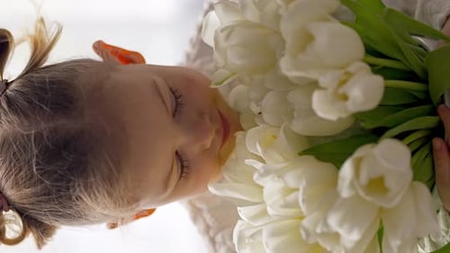 Cute Child Smelling White Tulips Bouquet Close Up
