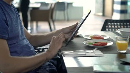Young Man Using Tablet and Drinking Juice in Cafe 30s