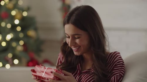 Woman Unwrapping Gift at Home During Christmas