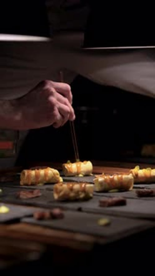 Chef Decorating Appetizers With Chopsticks in Restaurant Kitchen