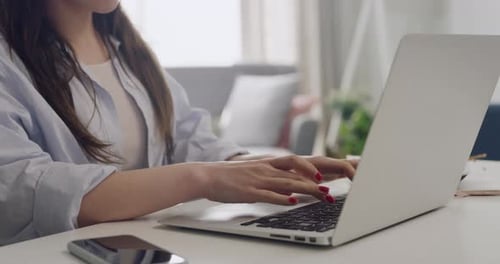 Woman Typing on Laptop at Desk in Home Office