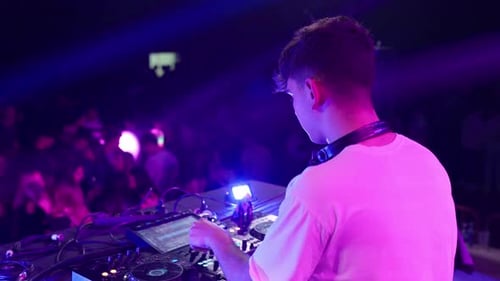 Energetic DJ Performing at Nightclub for Dancing Crowd