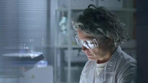 Female Researcher Examining Vial in Laboratory Setting