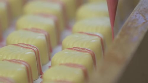 decorating white chocolates with pink garnish lines