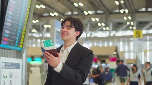 Asian businessman passenger checking departure boarding pass in airport.