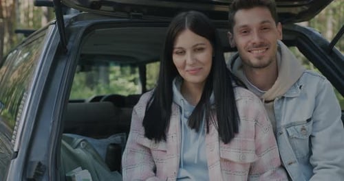 Smiling Couple Sitting in Car at Rural Campsite