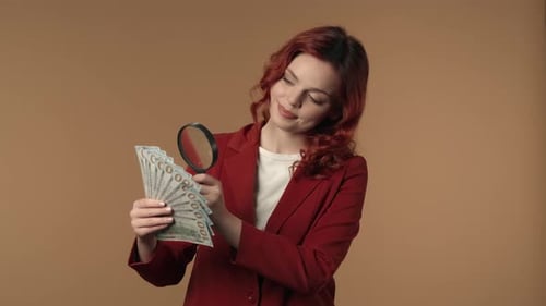 Woman Examines Money with Magnifying Glass
