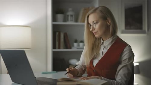 Woman Working at Computer and Writing in Notebook
