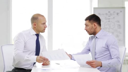 Business, Partnership, Finances and Office Concept - Two Serious Businessmen Holding Papers