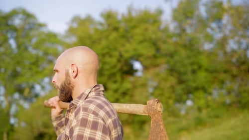 Holzfäller legt eine Axt auf seine Schulter und starrt auf eine wunderschöne Landschaft mit grünem m