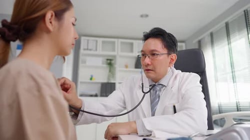 Asian cardiologist doctor listen to heartbeat patient woman in hospital.