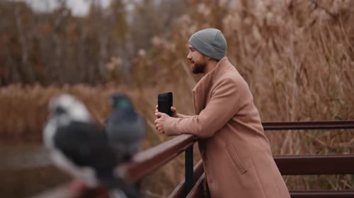 Man Drinks Coffee and Relaxes by the Lake