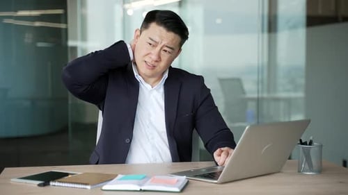 Man Massaging Neck from Pain at Office Desk