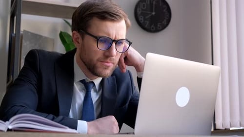 A Young Businessman Works with a Laptop in the Office
