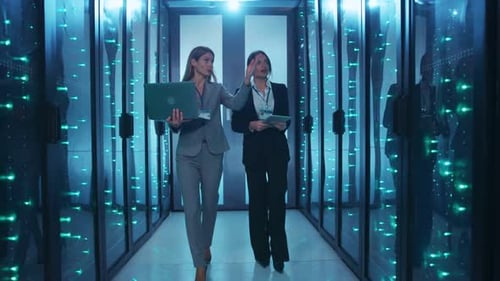 Two Women Discuss Technology in a Data Center Showcasing Teamwork