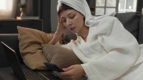 Woman in Robe Relaxing on Couch with Phone
