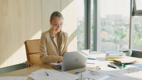 In a Modern Office with City Views a Professional Woman Works on Her Laptop Enjoying the Bright