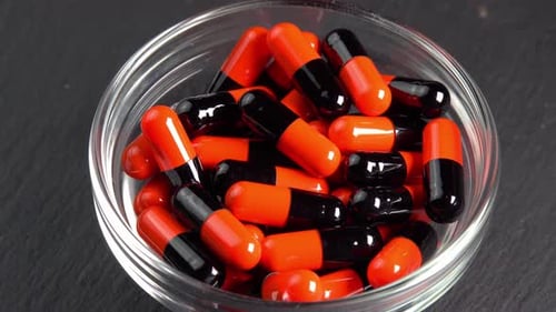 Orange and Black Pills in Glass Bowl