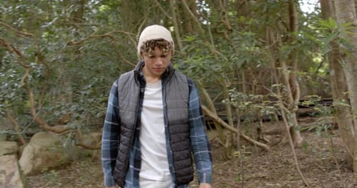 Young man exploring forest, wearing warm clothing, enjoying nature walk
