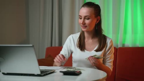 Young Woman Counts and Hands Out Cash to Pay Bills at the Table