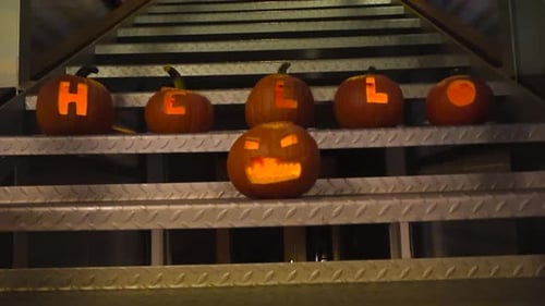 Abóboras de Halloween que têm esculturas e soletram a palavra olá em uma escada de metal cinza
