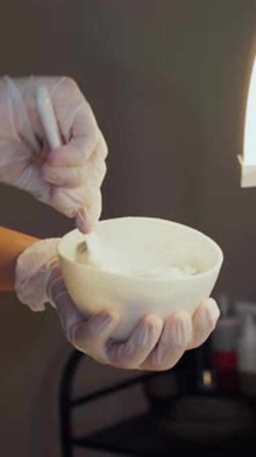 Professional Preparing a White Cosmetic Mask in a Small Ceramic Bowl