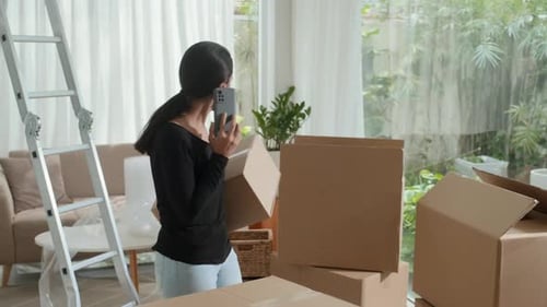 Woman Talking on Smartphone While Holding Box