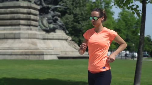 Young woman jogger taking a break in city park super slow motion