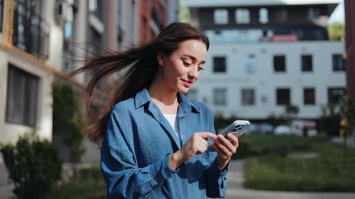 Young Woman Typing on Smartphone in Urban Setting