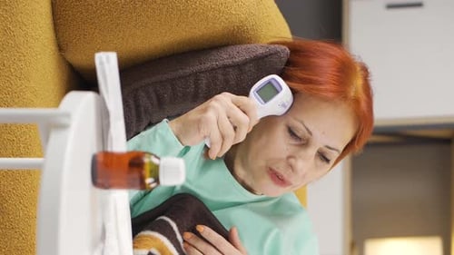 Vídeo vertical de mulher madura doente mede sua temperatura.