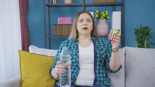 The sick young woman drinks a lot of water.