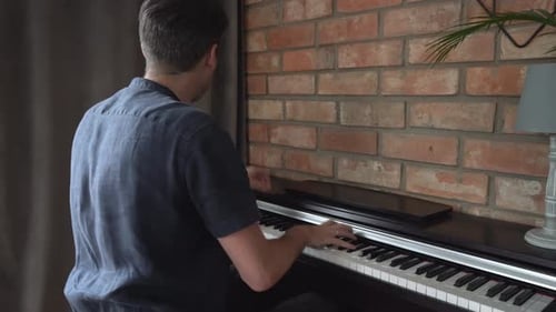 Adult Playing Piano at Home Near Brick Wall