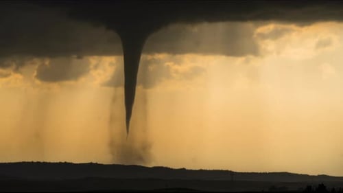 Dunkler Tornado dreht sich bei starkem Regen unter schwarzen Sturmwolken